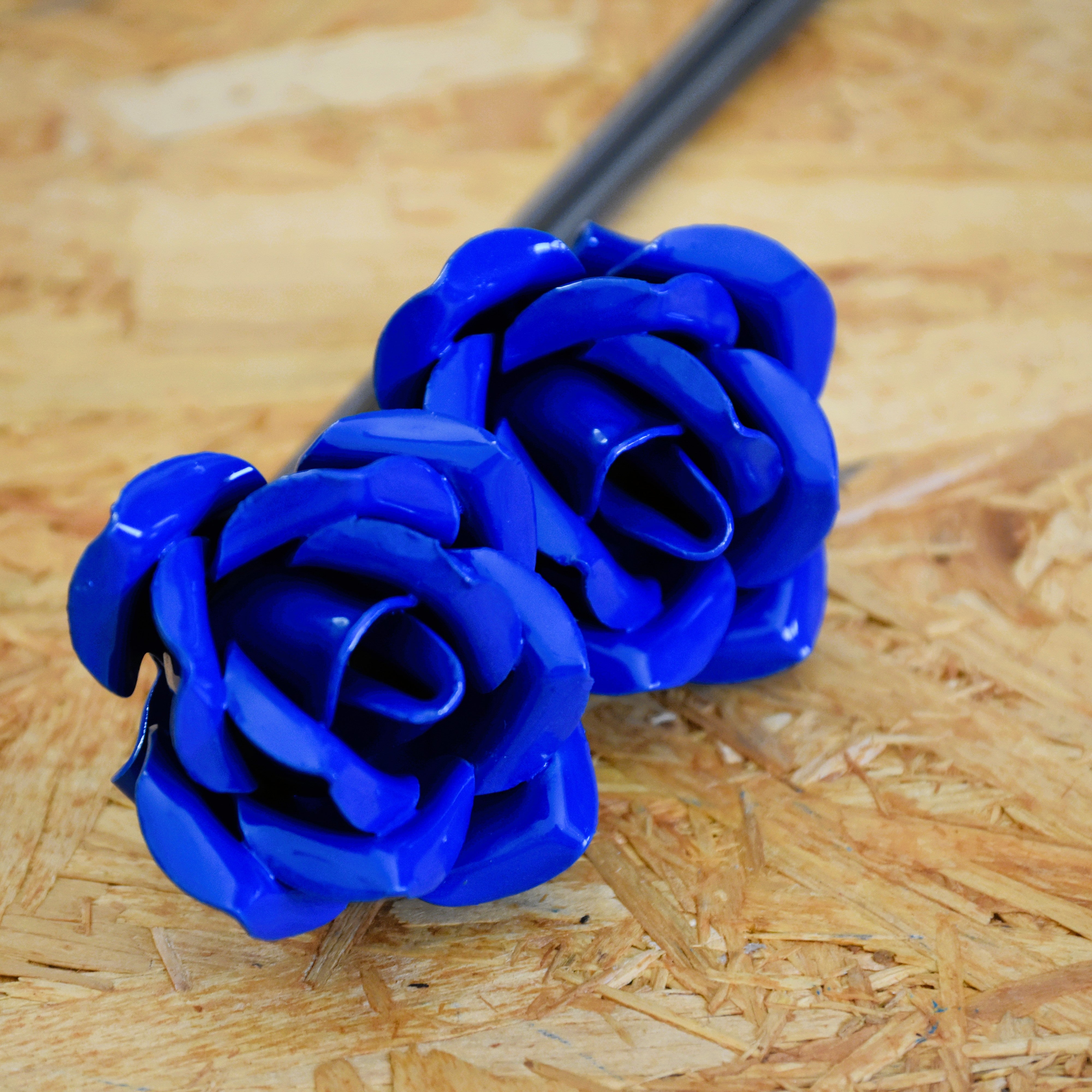 A closeup of two blue painted steel roses