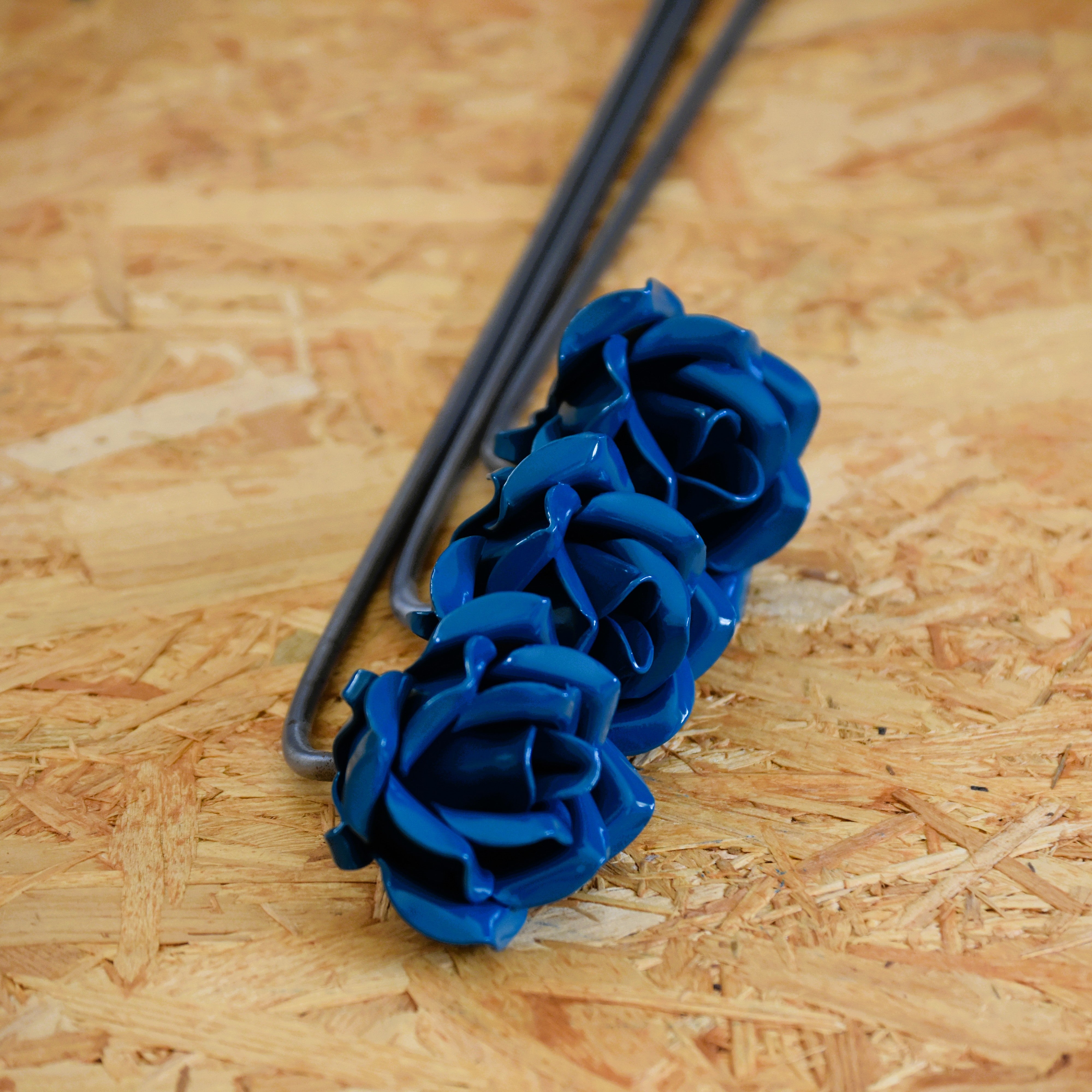 A closeup of three dark turquoise coloured steel roses