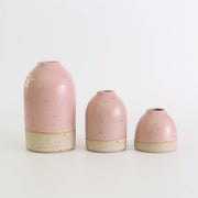 Three pink ceramic vases of different sizes on a white background