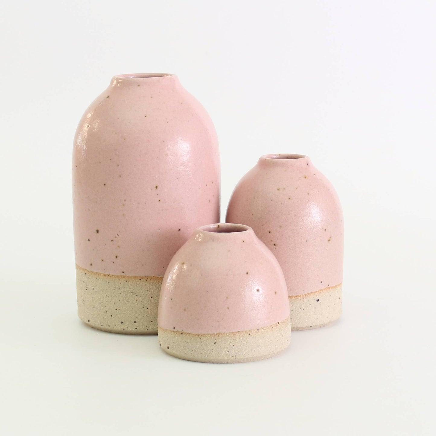 Three pink ceramic vases of different sizes on a white background