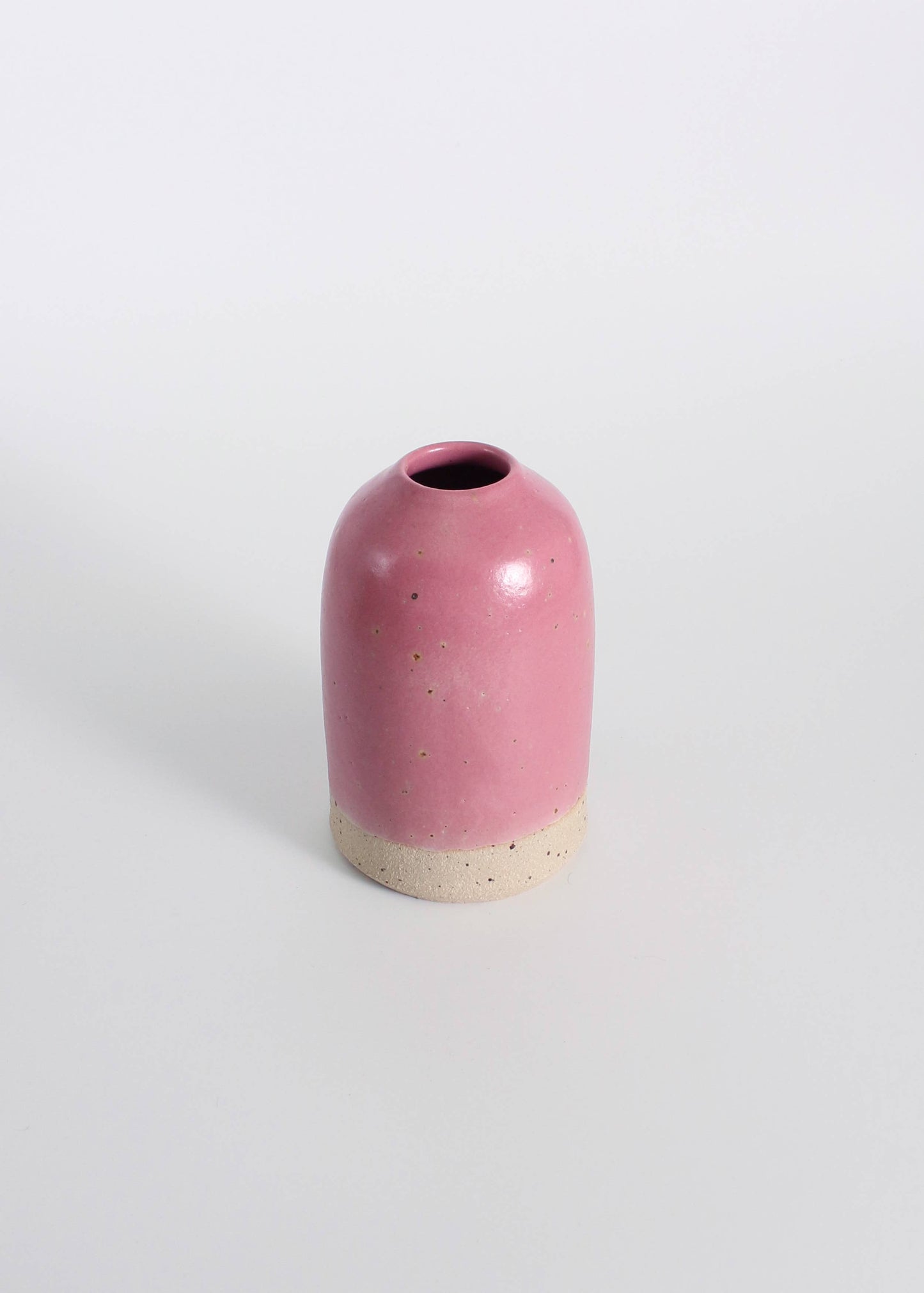 Fuchsia ceramic vase with a natural base on a white background