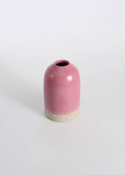 Fuchsia ceramic vase with a natural base on a white background