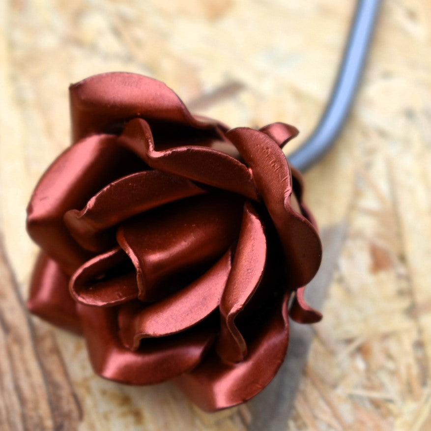 A copper coloured painted steel rose in closeup