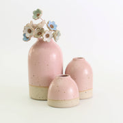 Set of three pink ceramic vases with speckled texture on a white background